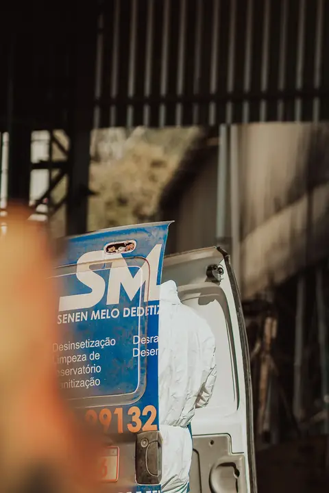 Banner da Senen Melo ao lado do veículo da empresa, com um profissional de macacão ao fundo.