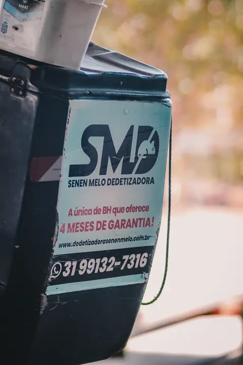 Baú de motocicleta com o logotipo SMD da Senen Melo Dedetizadora e o telefone de contato.
