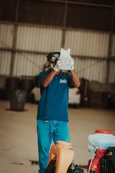 Profissional com uniforme da Senen Melo segurando um frasco à altura dos olhos, com equipamentos ao lado.