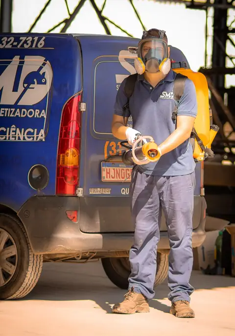 Profissional com uniforme da Senen Melo, máscara facial e equipamento portátil em frente ao veículo da empresa.